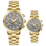 Branded couple wrist watches in pakistan. A pair of gold-toned watches with white analog dials, one large and one small, set against a black background.